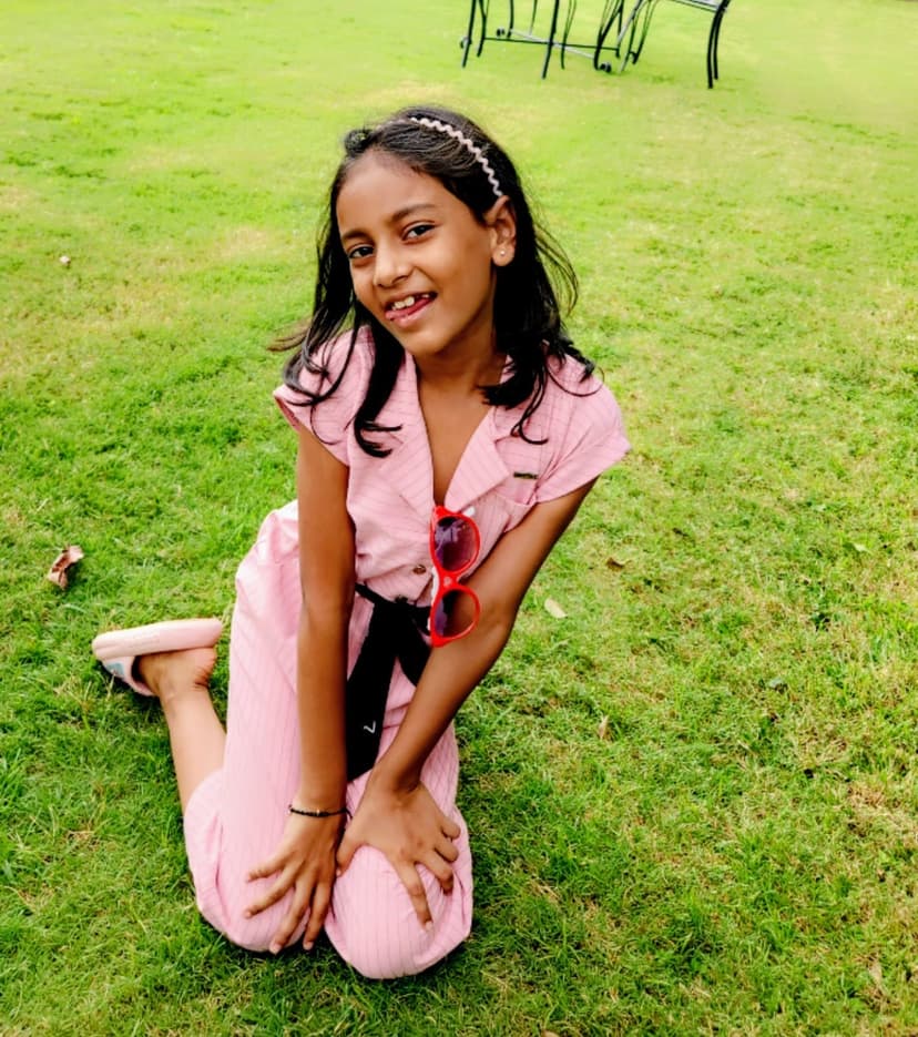 Khushi sitting on grass in pink outfit